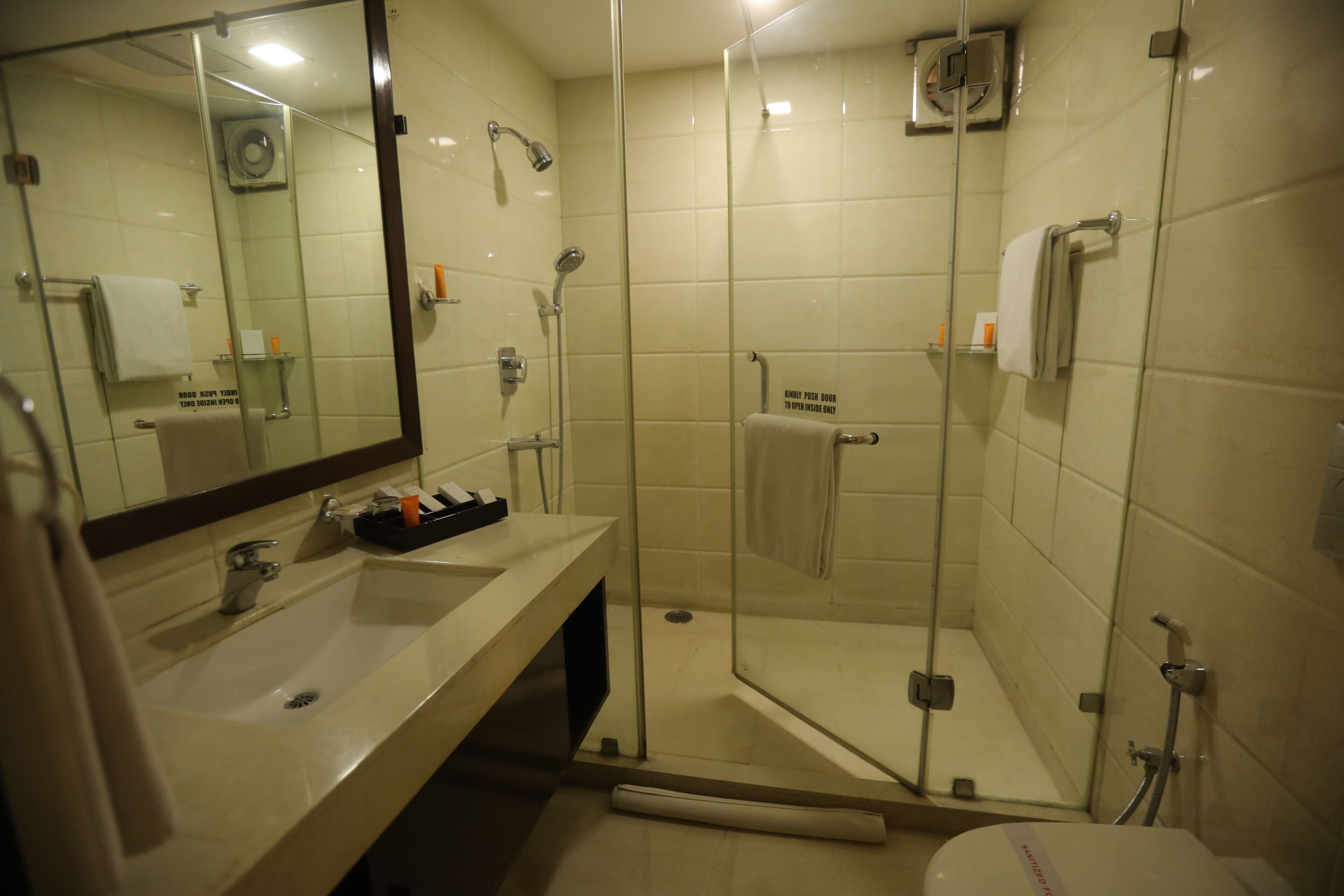 A modern bathroom with a glass-enclosed shower, a sink with a mirror, and a toilet.