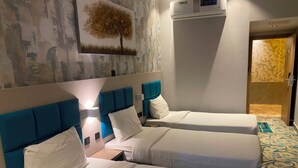 A hotel room with two beds, a wall-mounted air conditioner, and a door leading to another room. - Tamarind Hotel (Dubai)