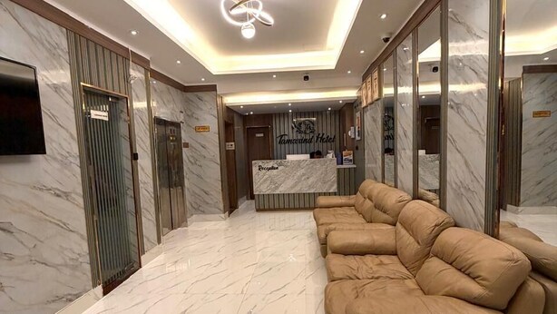 A hotel lobby with a reception desk, a sofa, marble flooring, and elevators. - Tamarind Hotel (Dubai)