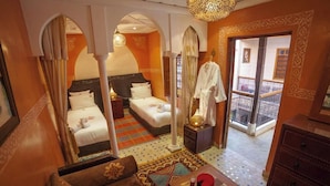 Habitació d'hotel amb dos llits, zona de seients i un balcó amb vistes.