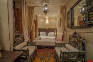 A traditional room with a large bed, two sofas, a chandelier, and ornate decor. - Riad Ikalimo 1 (Marrakech)