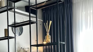 A modern room with a black metal shelving unit, a wooden desk, and a black leather chair.
