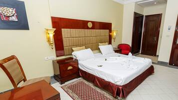 Habitació d'hotel amb un llit gran, taules de nit, una cadira i una catifa.