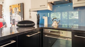 A modern kitchen with a built-in oven, a kettle, and a coffee maker on the counter.