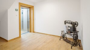 Una stanza con pavimento in legno, una macchina da cucire e una porta che dà su un'altra stanza.