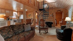 A log cabin interior with a living room, kitchen, and a spiral staircase. - Private Wooded Log Cabin Near Shanty Creek Resorts -Four Season Adventure Awaits (Bellaire)