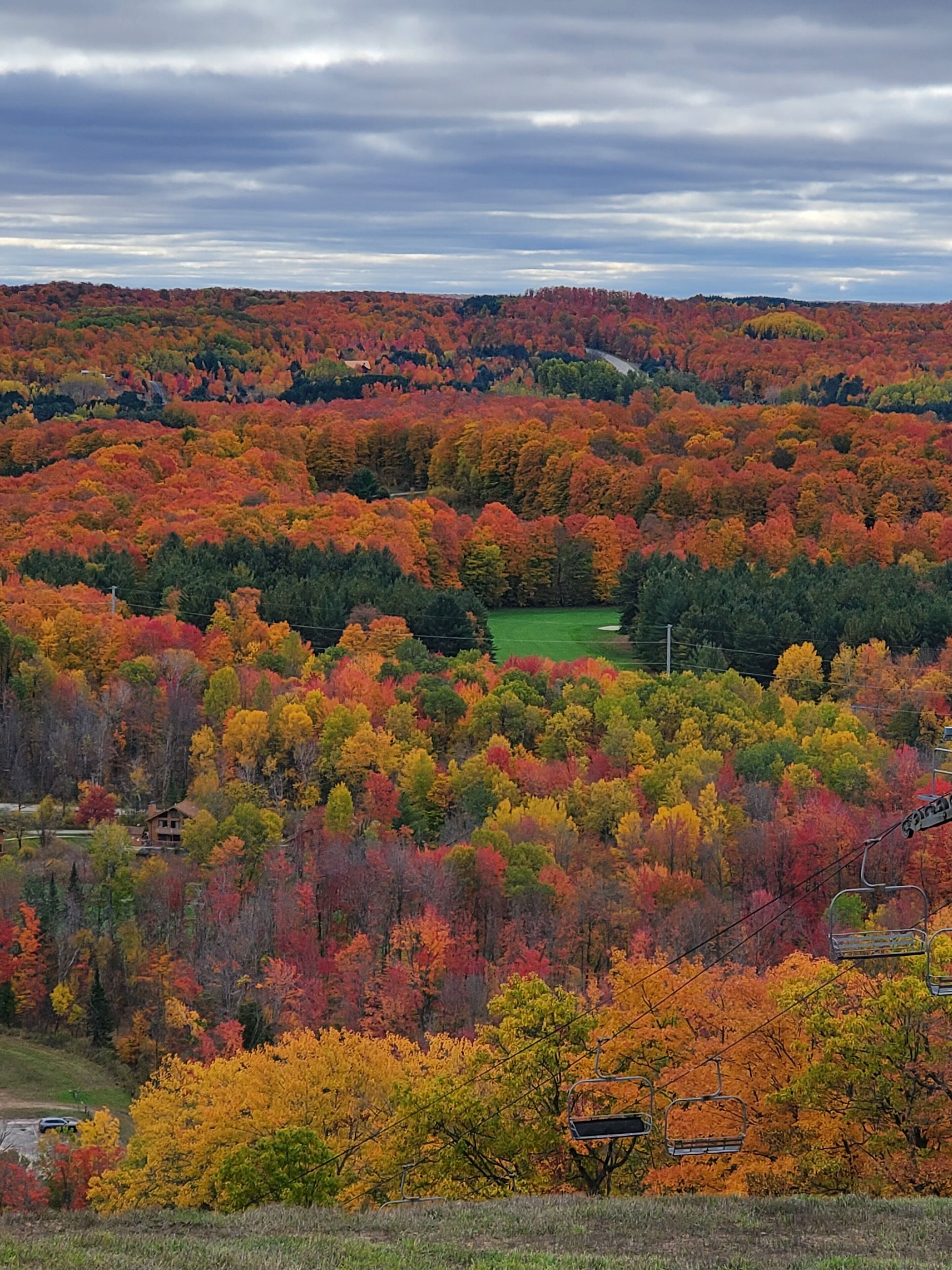 A mountainous landscape with autumn foliage, a ski lift, and a cabin.