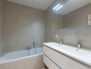 Une salle de bain moderne avec une baignoire, deux lavabos et un grand miroir.