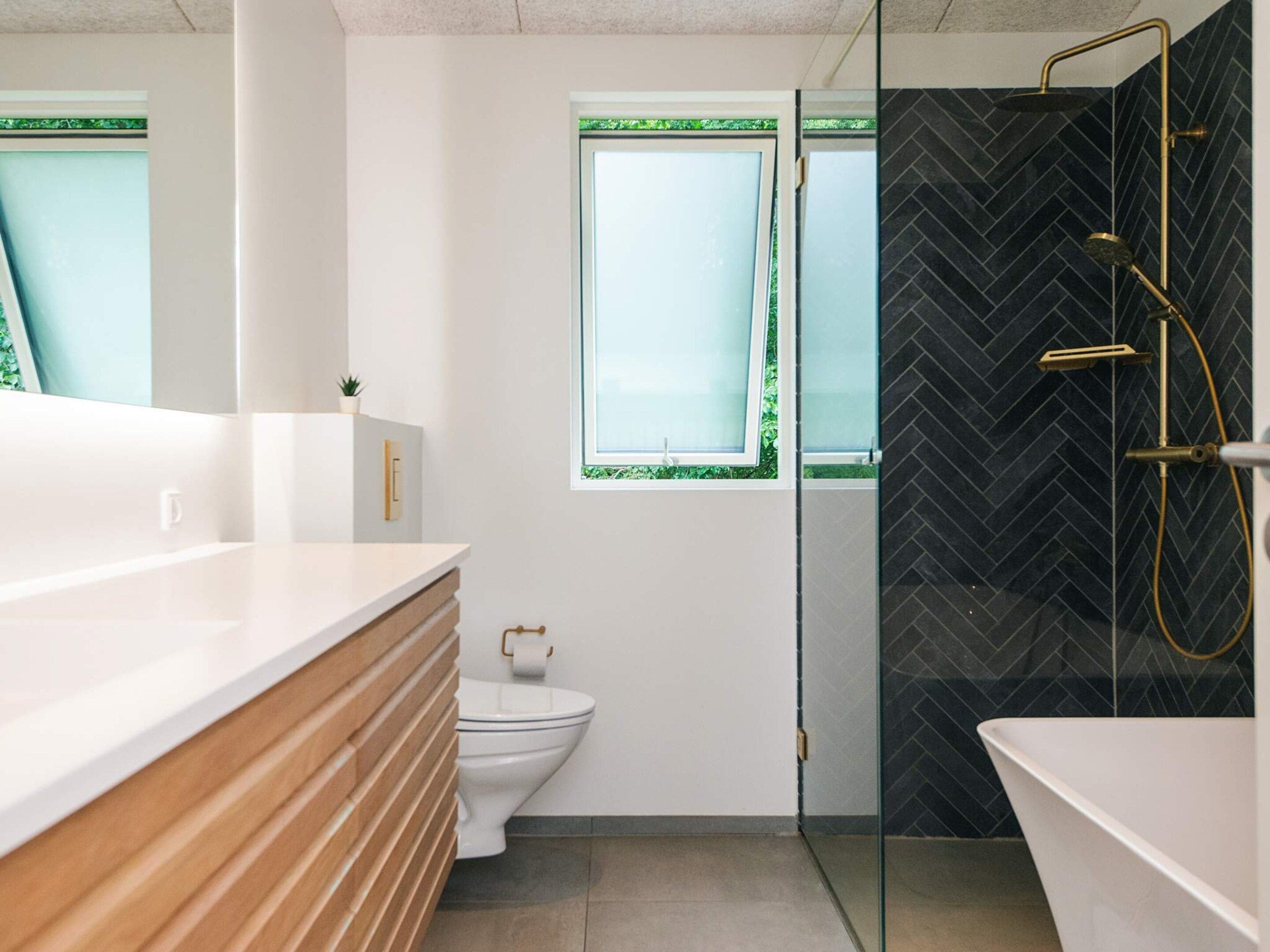 A modern bathroom with a glass shower enclosure, a toilet, and a sink with a wooden vanity.