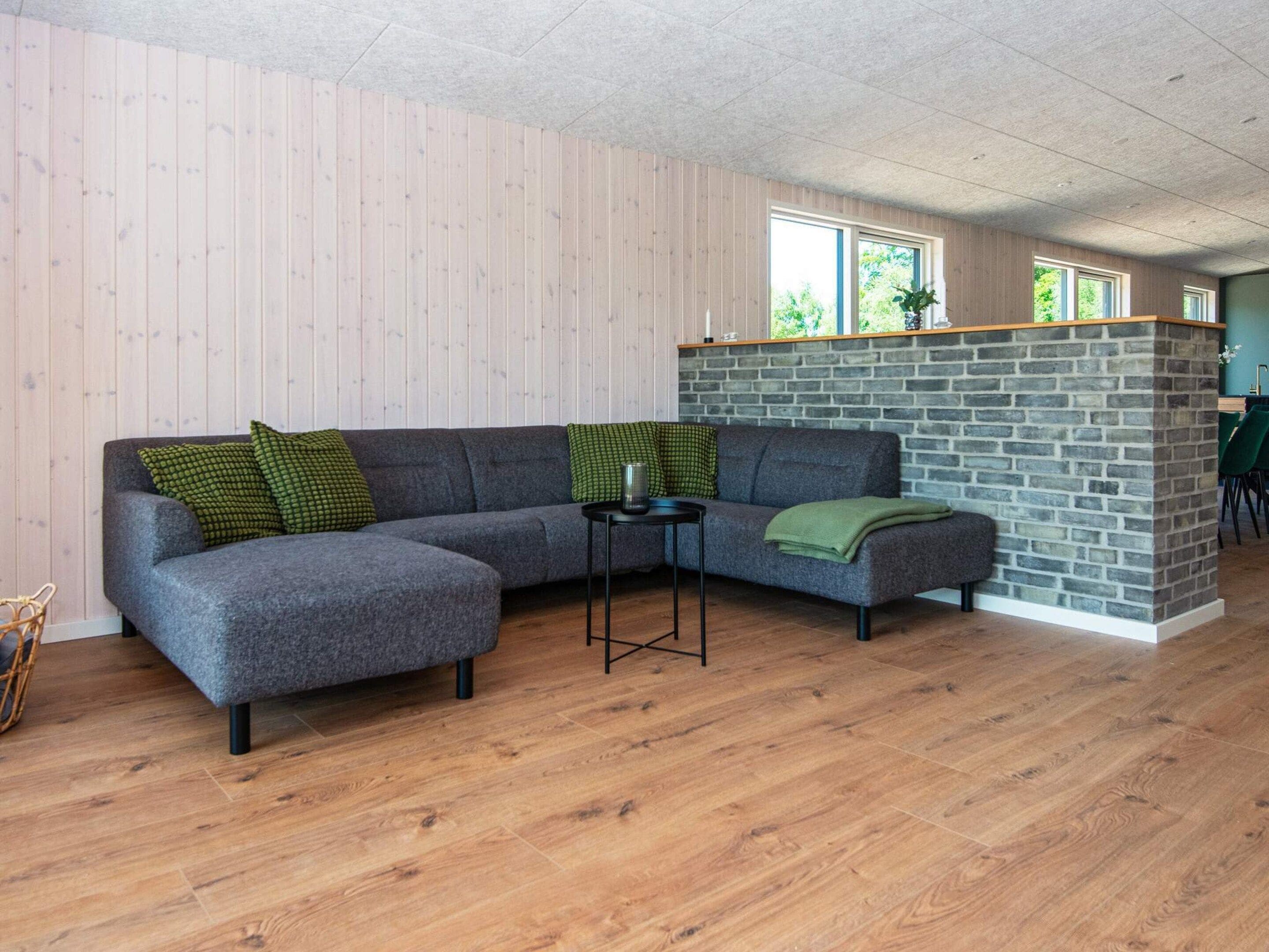 A modern living room with a grey sectional sofa, a small side table, and a stone accent wall.