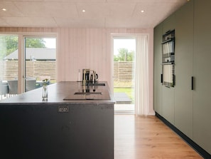 Una cocina moderna con una isla central, piso de madera y vista al exterior.