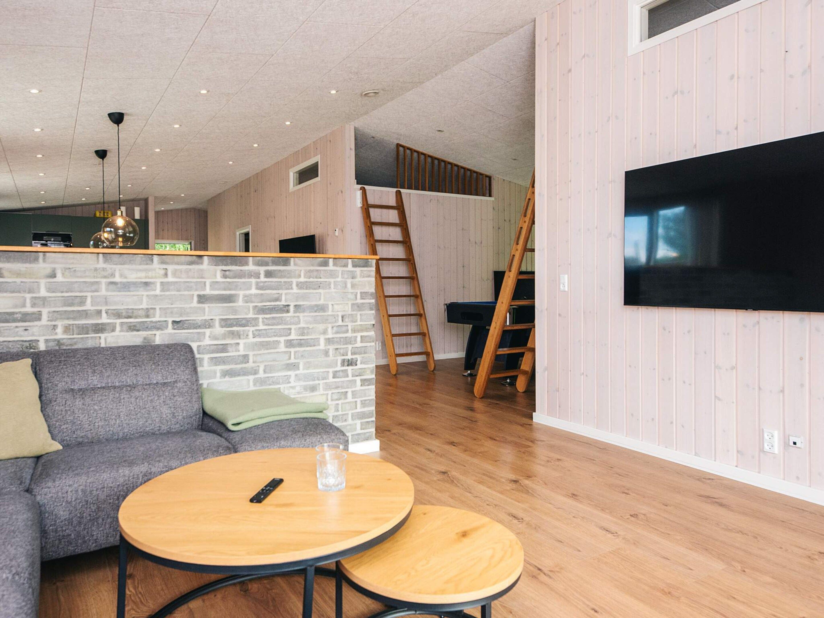 A modern living room with a sofa, a round coffee table, and a television mounted on the wall.
