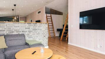 A modern living room with a sofa, a round coffee table, and a television mounted on the wall.