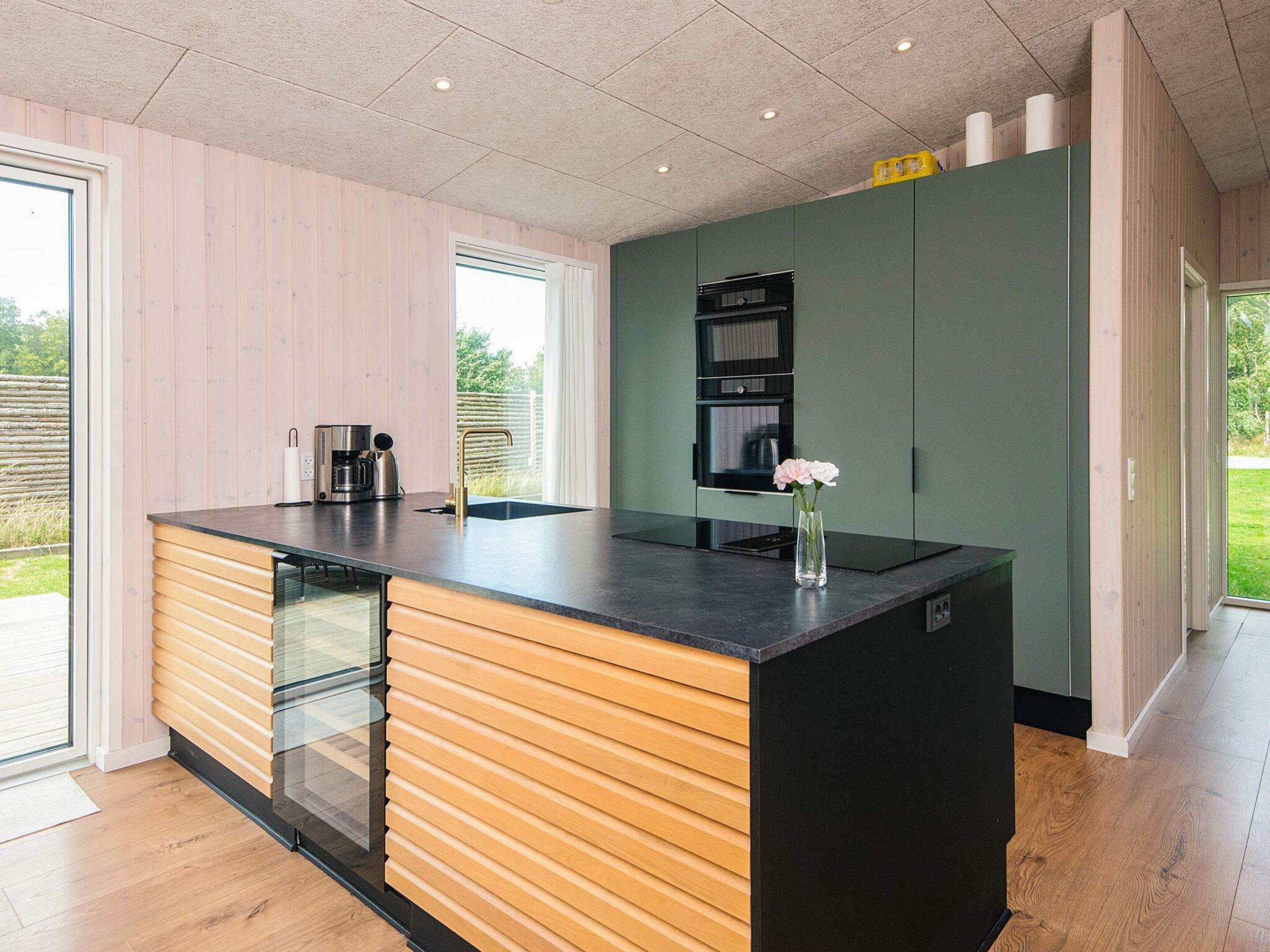 Una cocina moderna con una isla grande, electrodomésticos integrados y vistas al exterior.