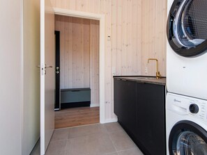 Une petite buanderie équipée d’un lave-linge, d’un sèche-linge et d’un petit évier.