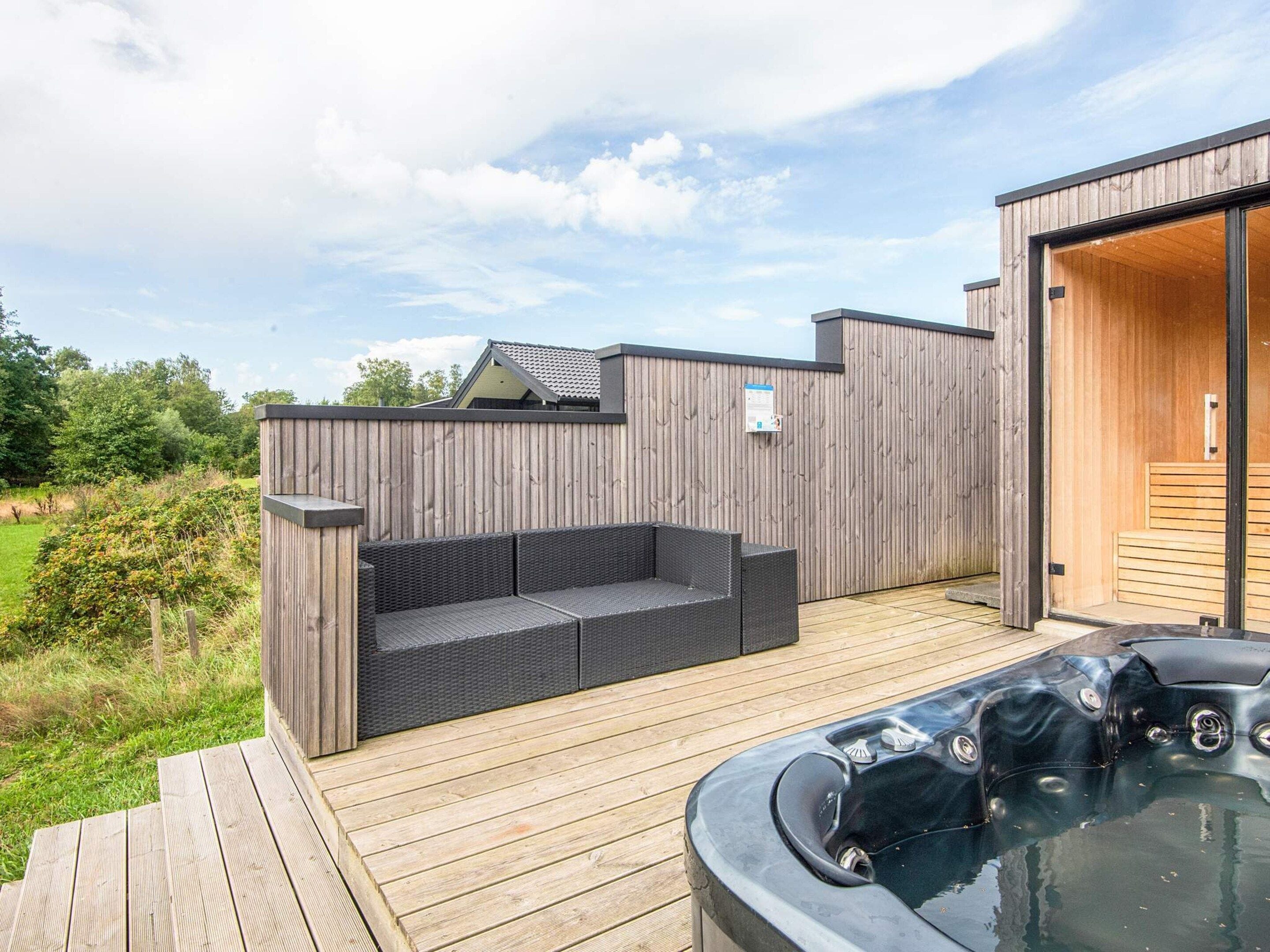 A wooden deck with a hot tub, a built-in seating area, and a wooden fence.