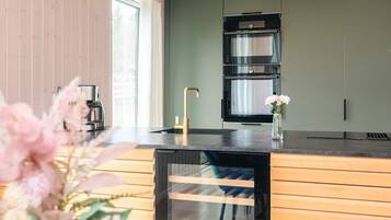 A modern kitchen with a built-in oven, a coffee machine, and a vase with flowers on the counter.
