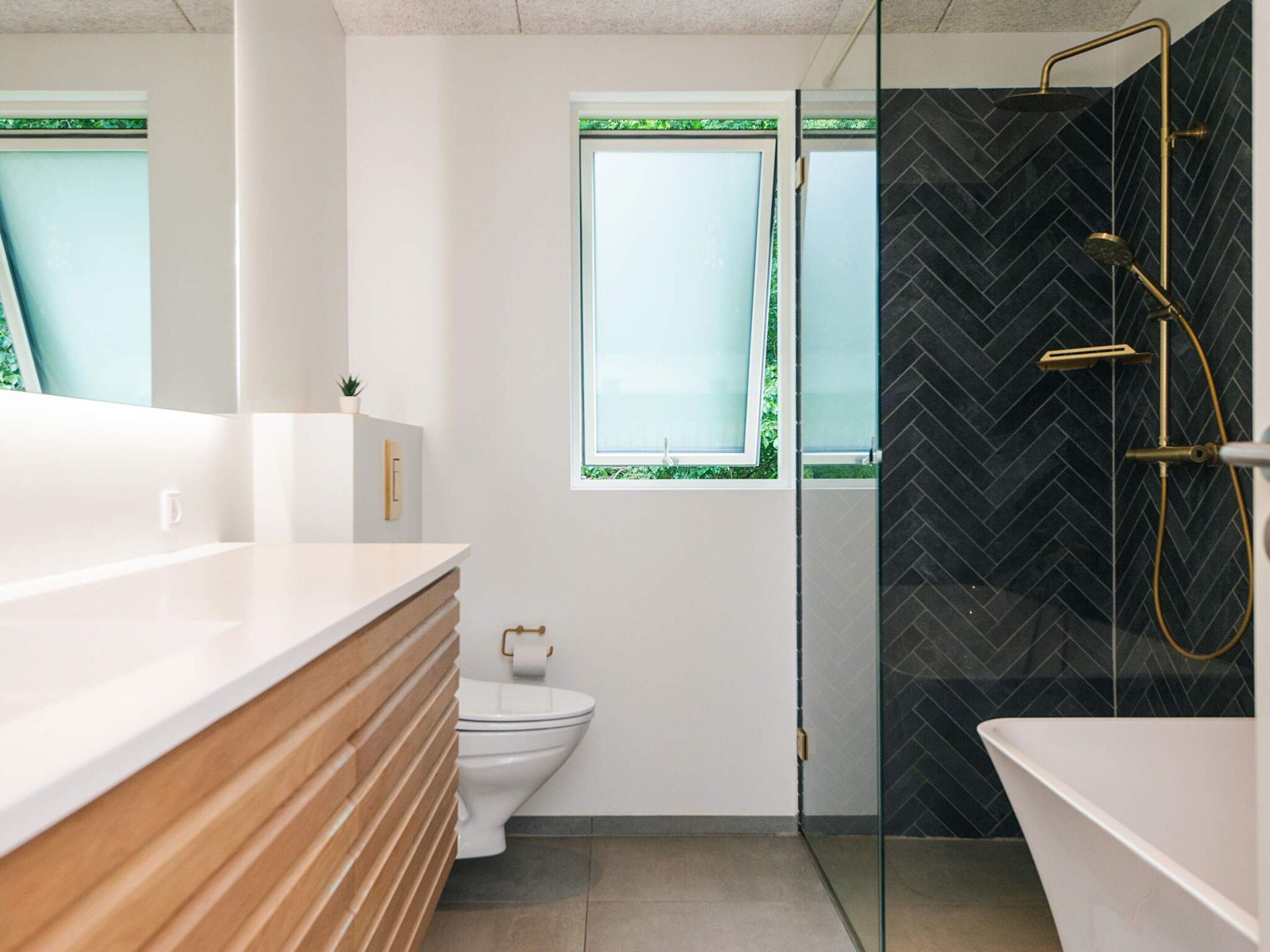 A modern bathroom with a glass shower enclosure, a toilet, and a sink with a wooden vanity.