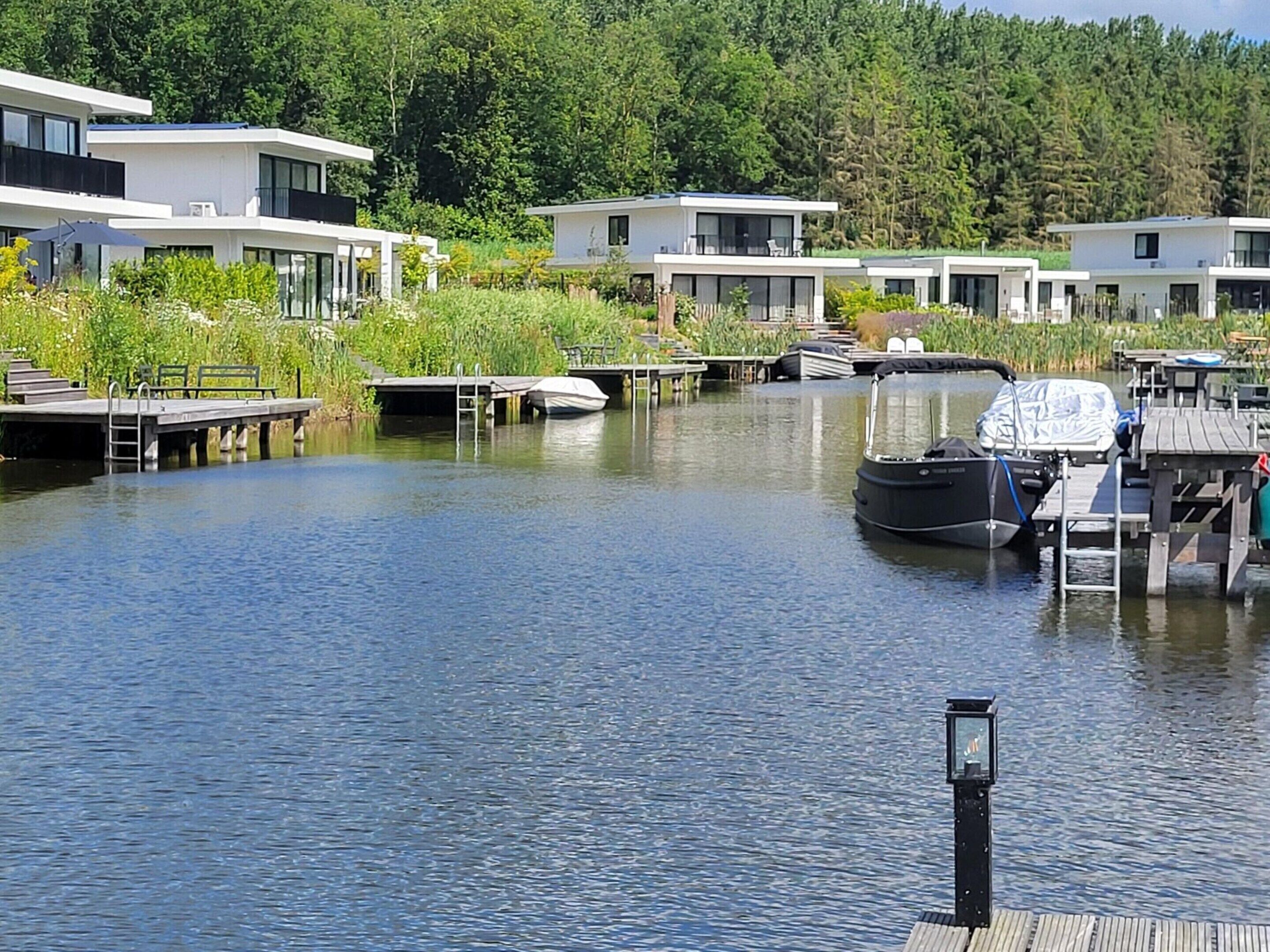 Een jachthaven met moderne huizen, liggende boten en een rustig waterlichaam.