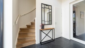 Un escalier moderne avec des marches en bois et une console en métal noir agrémentée d’un vase et de bougies.