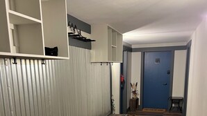 A hallway with a wooden floor, metal railings, and a blue door with a number sign.