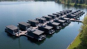 A marina with multiple floating structures, each with a covered deck and a small boat docked nearby. - Houseboat Mookerplas With a View (Middelaar)