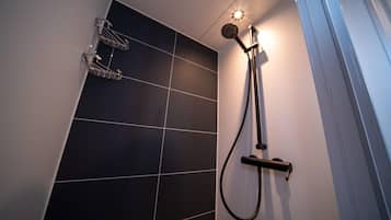 A shower with a handheld showerhead and a wall-mounted control.