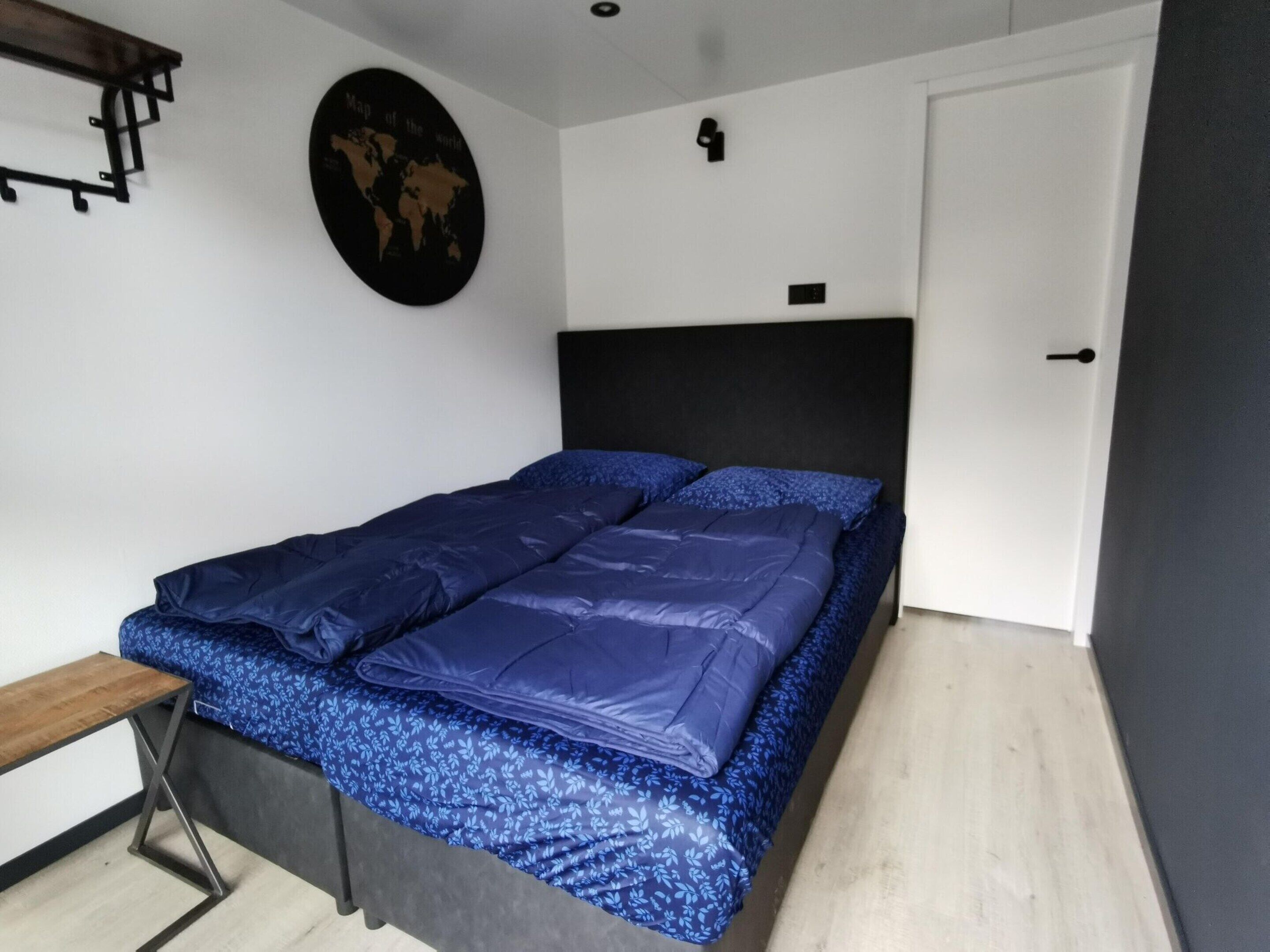 Une chambre à coucher avec un lit, un bureau et une carte du monde accrochée au mur.