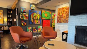 A modern living room with two orange armchairs, a round wooden table, and a fireplace.