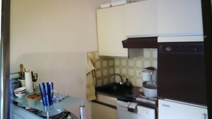 A compact kitchen with a dishwasher, a stove, and a refrigerator. - Le Moulleau Ctre, Front de Mer, Studio 2 Personnes Avec Terrasse (Arcachon)