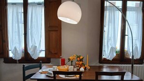 A dining area with a table set for two, a lamp, and a vase with flowers and oranges on the windowsill. - Guelfa56: delightful apartment with air conditioning in the center (Firenze)