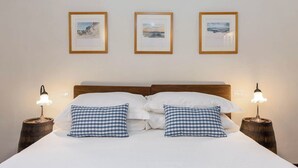 A bed with white linens, two checkered pillows, and a wooden headboard. There are three framed pictures on the wall above the bed. - Guelfa56: delightful apartment with air conditioning in the center (Firenze)