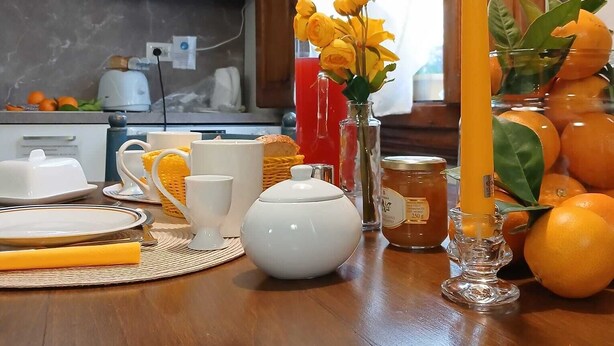 A kitchen with wooden cabinets, a microwave, and a dining table set with white dishes, a teapot, and a vase of yellow flowers. - Guelfa56: delightful apartment with air conditioning in the center (Firenze)