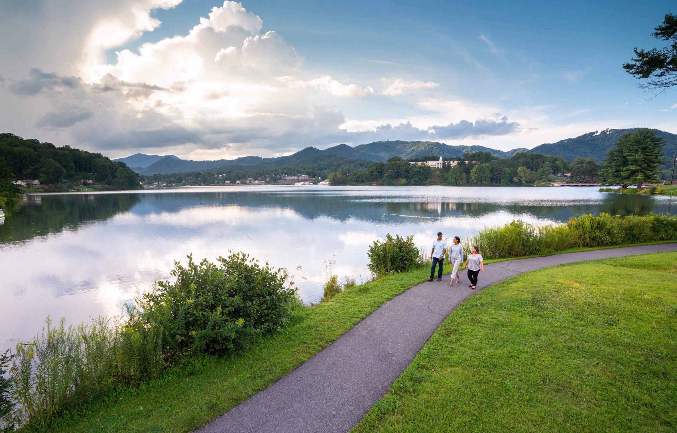 A lake with a walking path and a few people walking.