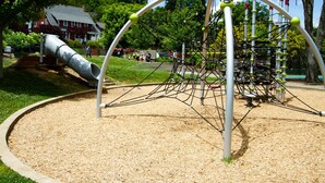 A playground with a slide and climbing structures. - Hillside Lodge (Lake Junaluska)