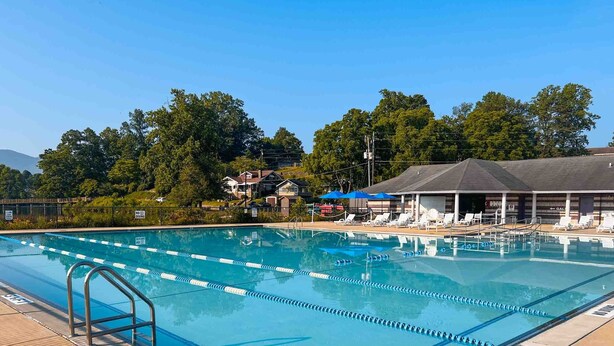 A swimming pool with lane dividers, a diving board, and lounge chairs. - Hillside Lodge (Lake Junaluska)