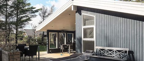 A modern outdoor deck with a dining area, lounge chairs, and a built-in bench.