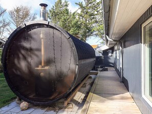 A large cylindrical structure, possibly a water tank, on a wooden deck outside a building with a modern design. - 8 Person Holiday Home in Lokken (Lokken)