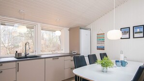 Una cocina moderna con comedor, que cuenta con un amplio ventanal, un lavabo y una mesa con sillas.