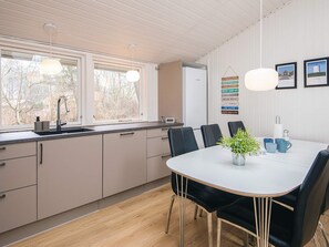 A modern kitchen with a dining area, featuring a large window, a sink, and a table with chairs. - 8 Person Holiday Home in Lokken (Lokken)