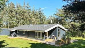 Una casa moderna con una amplia terraza, un trampolín y un jardín.