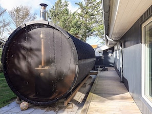 A large cylindrical tank outdoors, possibly for water storage, next to a building with a wooden deck.