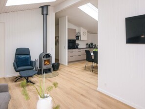 A modern living room with a wood-burning stove, a dining area, and a kitchen. - 8 Person Holiday Home in Lokken (Lokken)