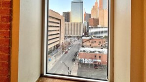 Ein Fenster mit Blick auf eine Stadtlandschaft, inklusive Gebäude und einer Straße.