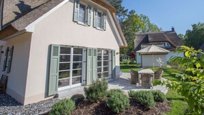 A house with a large front porch, a thatched roof, and a garden with a stone bench. - Holiday Home Reet-seaside (Glowe)