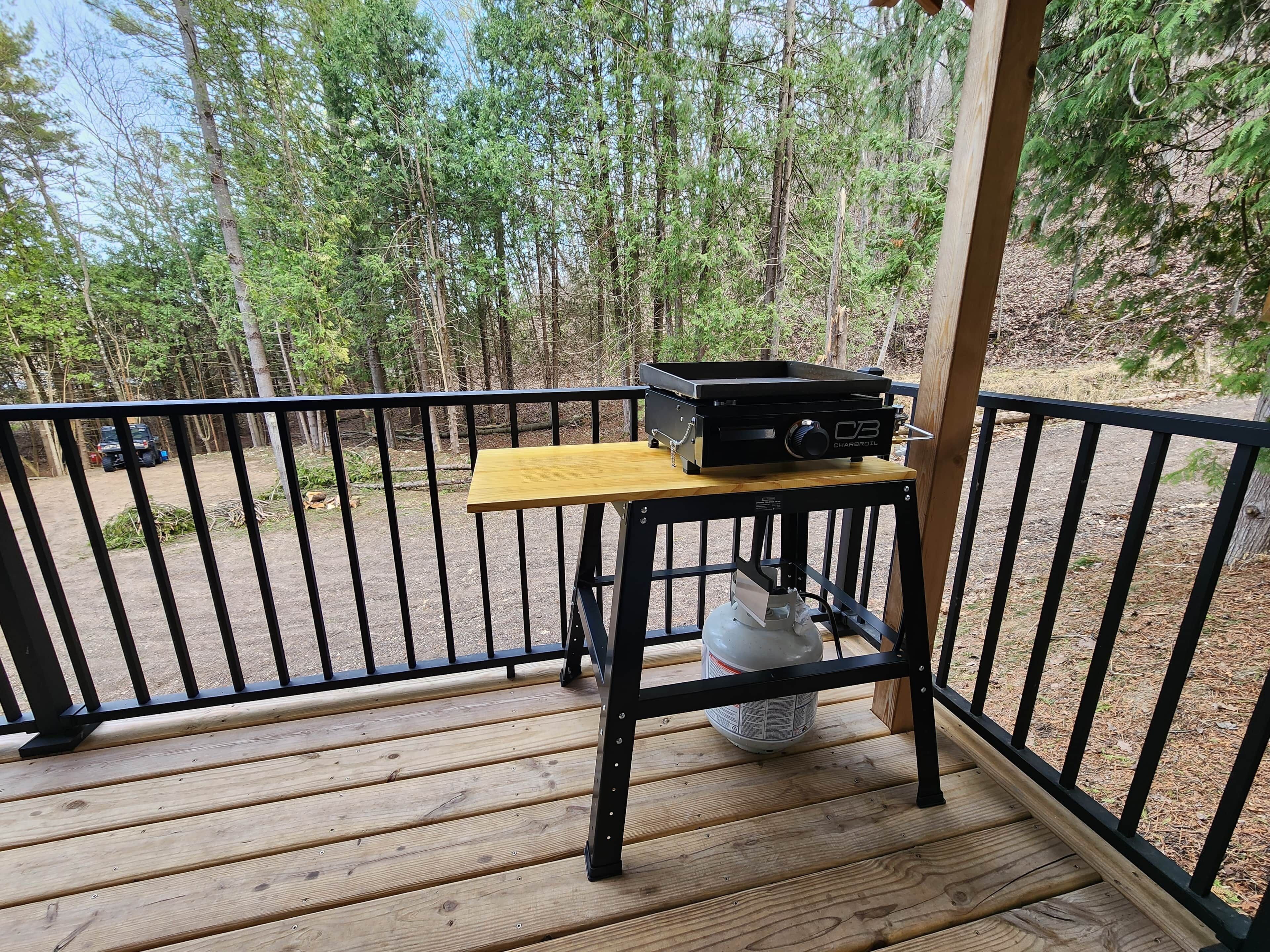 Eine Holzterrasse mit Grill, Tisch und Metallgeländer.