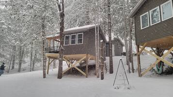 Una cabaña de madera con balcón, rodeada de árboles cubiertos de nieve.