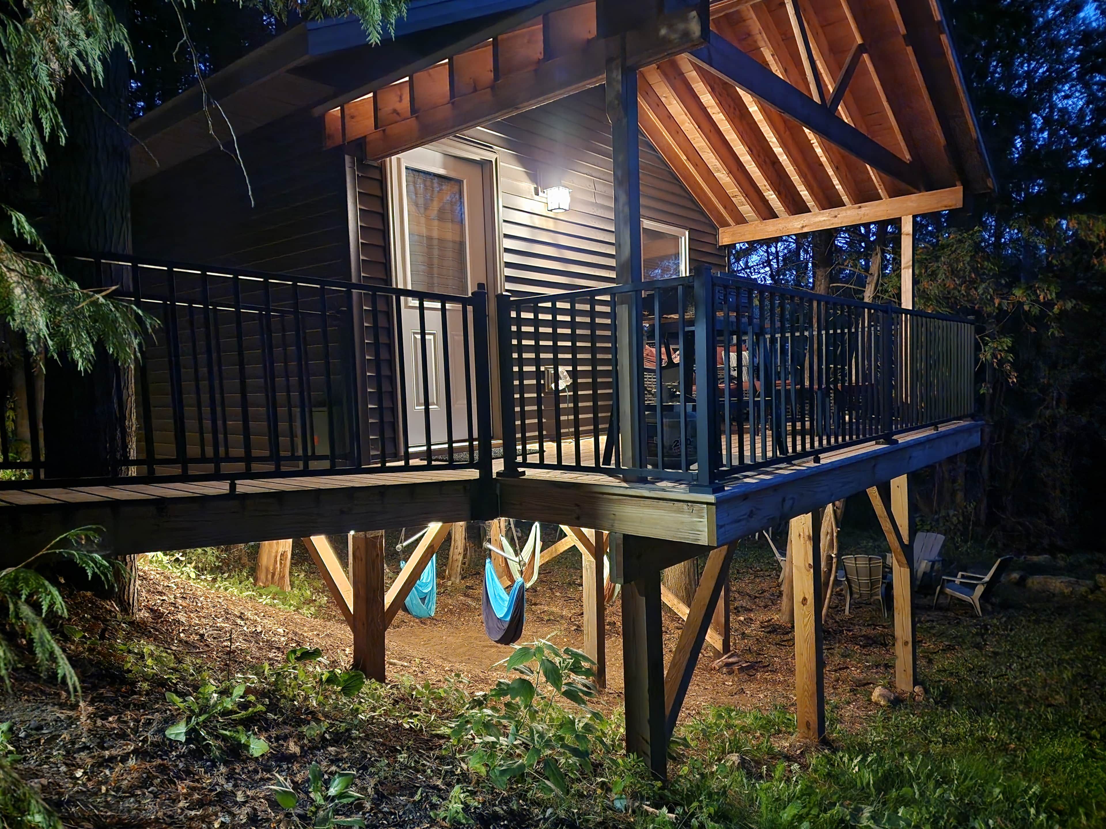 A wooden deck with a railing, surrounded by trees and vegetation.