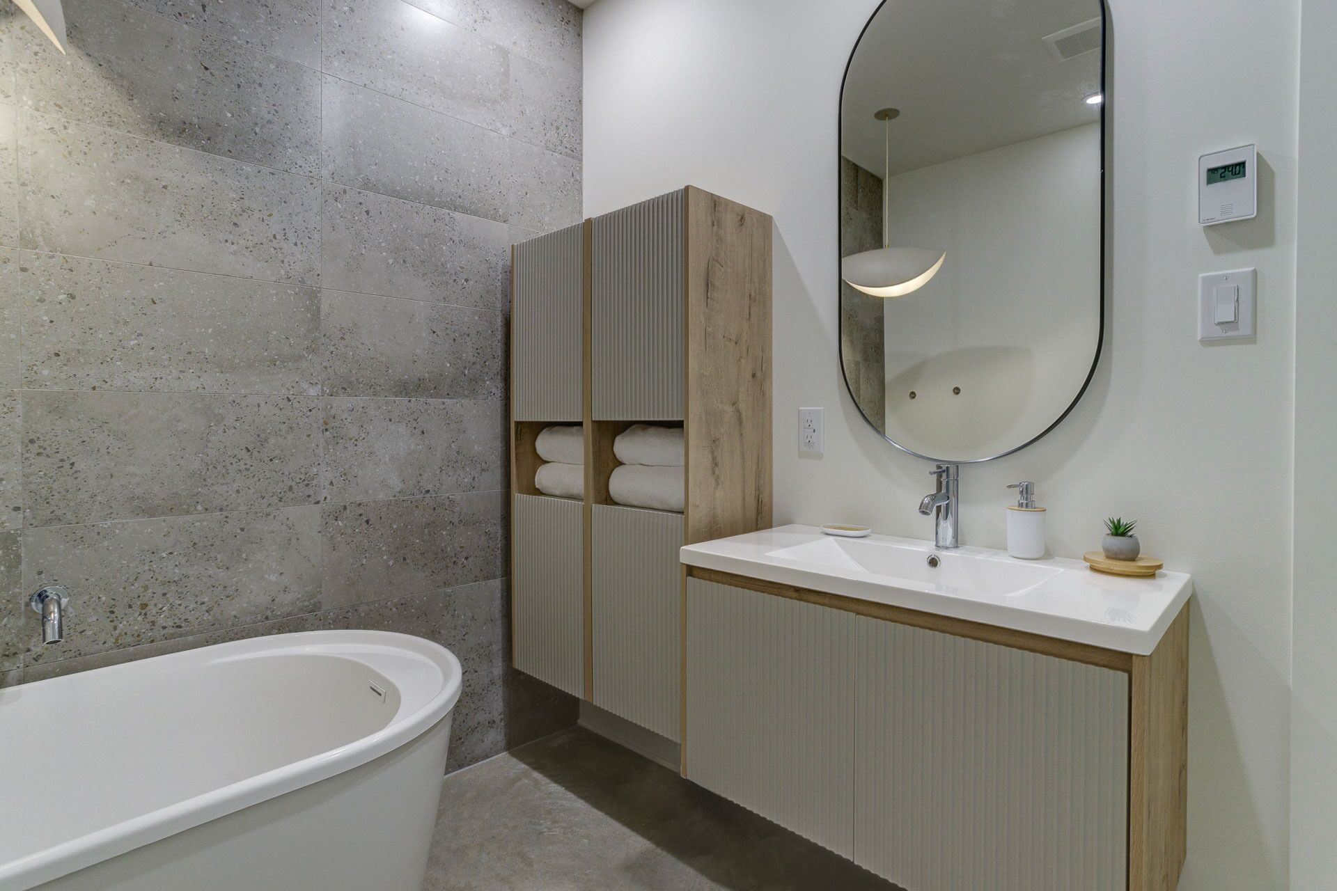 Une salle de bain moderne avec une baignoire sur pieds, un grand miroir et un meuble-lavabo en bois.