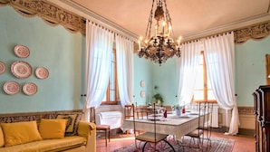 Ein Essbereich mit einem Tisch, der für vier Personen gedeckt ist, umgeben von Stühlen, einer Chandelierleuchtre und einem gemusterten Teppich.